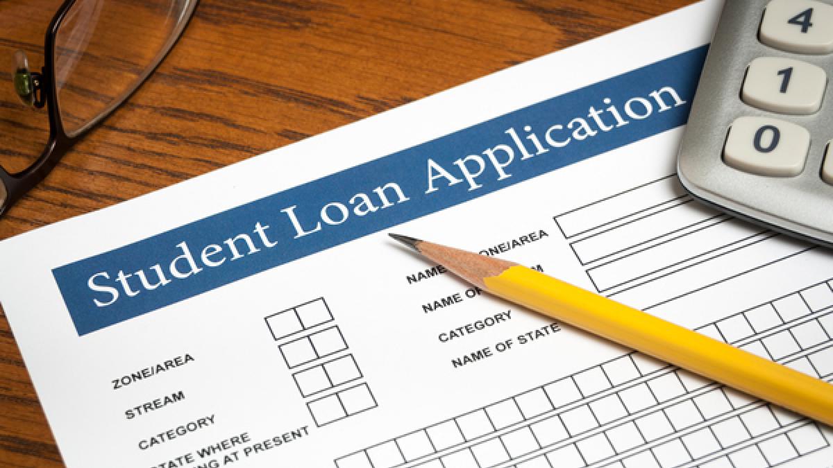 Student loan application with pencil and calculator on a wooden desktop 