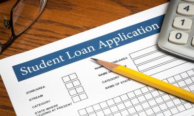 Student loan application with pencil and calculator on a wooden desktop 